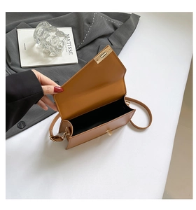 Detailed interior of a brown leather shoulder bag with metallic lock and black lining