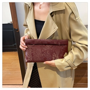 Close-up of wine red snake-patterned box bag with glossy texture and metal chain loops