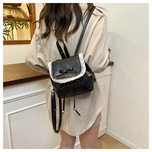 Model wearing a sweet black mini backpack with lace trim and bow on the back