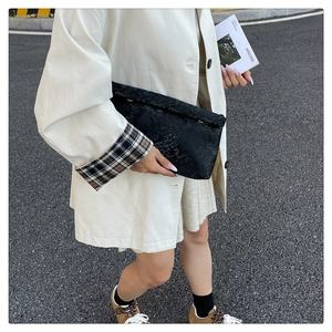 Detail of a large black snake skin envelope clutch bag held against a white coat