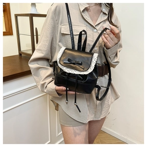 Detailed view of black PU leather mini backpack with white lace edges and bow detail