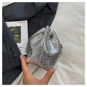 Detailed view of silver woven metallic bucket bag texture and shiny chain strap