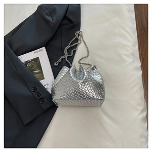 Detailed top view of a silver woven bucket bag styled with a blazer and magazine