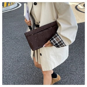Detail of dark brown snake print PU leather clutch bag with golden metal ring accent