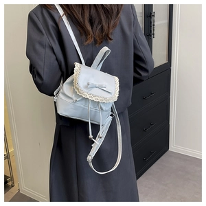 Rear view of a light blue mini backpack with white lace trim and bow on a model