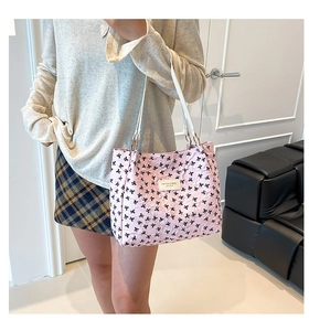 Pink tote bag detail with black bow print and leather fashion label on model