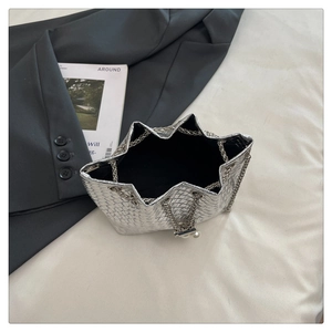 Close-up of silver woven handbag featuring star-shaped pleated opening and metal chain