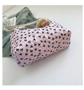 Detail of pink bubble fabric tote with black bows, leather strap and plush bear charm