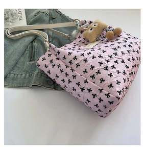 Detail of pink bubble texture tote bag featuring black bow prints and plush bear charm