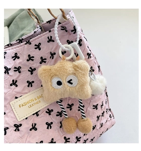 Close-up of a cute brown plush cartoon charm with long legs on a pink handbag detail