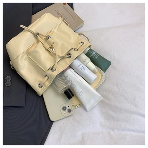 Detail of cream drawstring bucket bag showing front pocket and daily essentials capacity