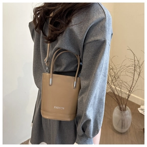 Detail of khaki bucket bag showing adjustable shoulder strap and silver metal hardware