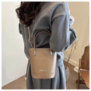 Detail of khaki leather bucket bag with adjustable strap and metallic fashion lettering