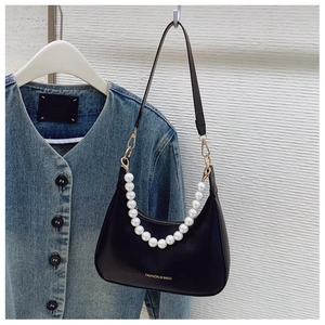 Detail of black underarm bag with large faux pearl handle and adjustable shoulder strap