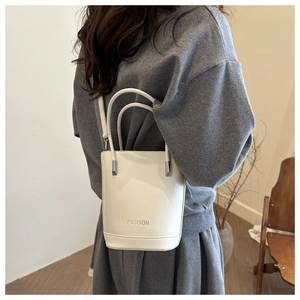 Minimalist beige bucket bag featuring silver metal accents and dual carrying handles