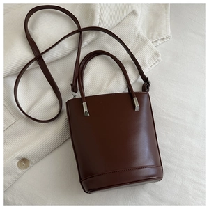 Detail view of smooth burgundy leather bucket bag with silver hardware on corduroy fabric