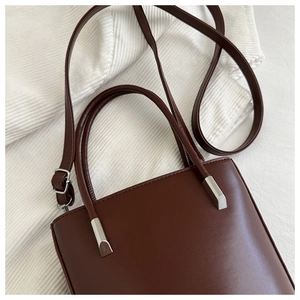 Detail of dark brown leather bucket bag showing silver hardware and handle texture