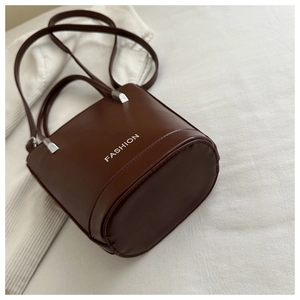 Detail view of the brown leather bucket bag with silver Fashion logo and sturdy stitching