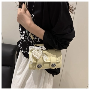 Détail du mini sac jaune en cuir avec nœud en dentelle et breloque cœur en perles