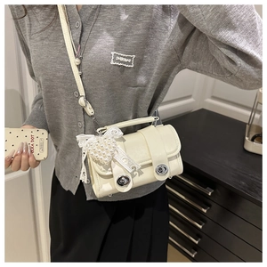Détail du mini sac crème avec verrous rotatifs argentés et breloque cœur perle