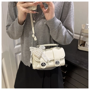 Detalle del mini bolso bandolera crema con colgante de perla corazón y cinta encaje
