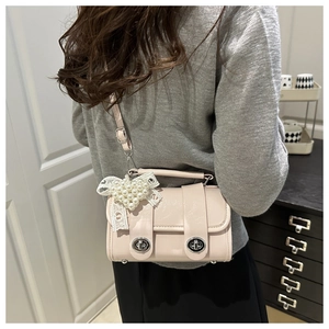 Détail du sac à bandoulière en cuir rose avec nœud en dentelle perlée et fermoirs rotatifs