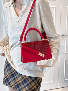 Elegant red crocodile textured leather handbag with gold twist lock and shoulder strap