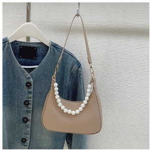 Detail of apricot faux leather underarm bag with elegant white pearl handle and metal zipper