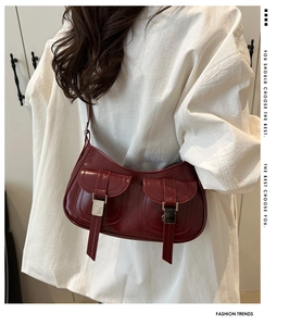 Detail of burgundy underarm bag showing glossy PU leather texture and silver buckle
