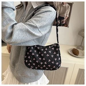 Détail du sac hobo matelassé noir avec broderie de nœuds roses et fermeture éclair