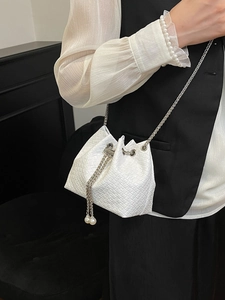 White woven bucket bag with pearl drawstring and silver chain strap for elegant daily styling