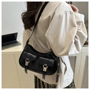 Detail of black faux leather shoulder bag with silver buckles and dual front pockets