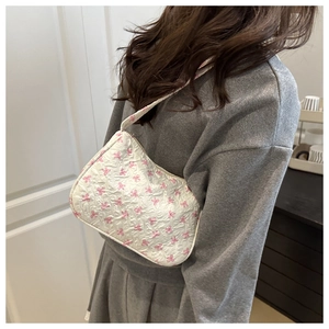 Detailed close-up of a white quilted shoulder bag featuring pink bow patterns