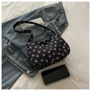 Vue de dessus d'un sac hobo noir avec broderie de nœuds roses et texture froissée