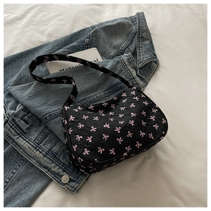 Détail du sac à bandoulière en jacquard noir avec motifs nœuds roses sur fond blanc