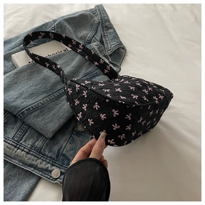 Détail du mini sac noir avec motif de nœuds roses et texture en jacquard plissé