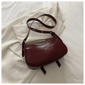 Detailed view of dark burgundy leather underarm bag with silver grommets on strap