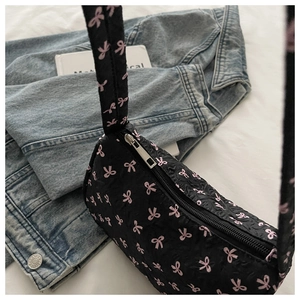 Détail d'un sac porté épaule matelassé noir avec motifs nœuds roses et zip argenté