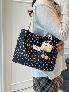 Trendy black quilted tote bag with pink bow patterns and a plush monster charm