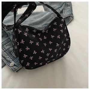 Détail d'un sac hobo plissé noir avec motifs nœuds roses et fermeture éclair argentée