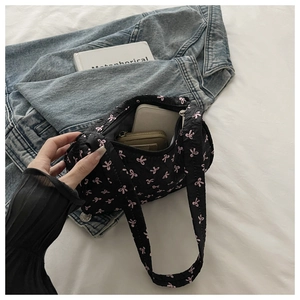 Vue intérieure d'un sac hobo matelassé à nœuds roses montrant le rangement du portable