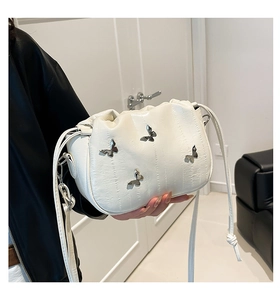 Detailed shot of white pleated bucket bag with silver butterfly charms and leather strap