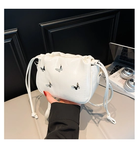 Detail showing the white PU leather texture and silver butterfly charms on the bucket bag
