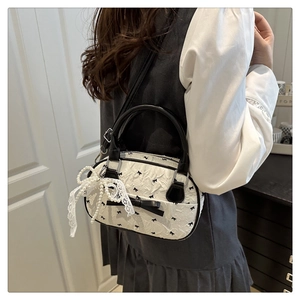 Close-up of white bow pattern shell bag with black handle and lace pearl charm detail