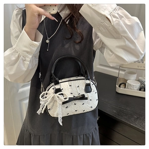 Détail du mini sac boston blanc avec imprimé nœud noir et breloque en perles