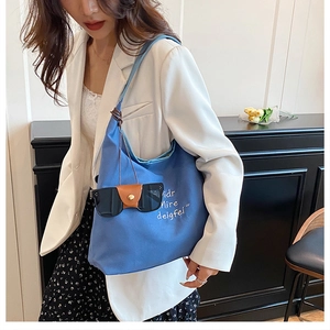 Detail of blue canvas hobo bag with white script print and sunglasses accessory