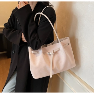 Detail of beige leather tote bag featuring a silver buckle strap and textured finish