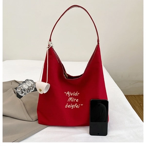 Detail of red canvas tote bag with white embroidery, leather strap and mini coin pouch