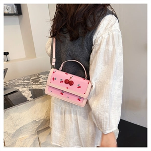 Dettaglio della piccola borsa rosa con stampe di ciliegie e ornamento in strass lucido