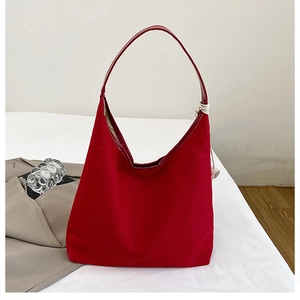 Detail showing the spacious red canvas hobo bag with a wide shoulder strap and white stitching